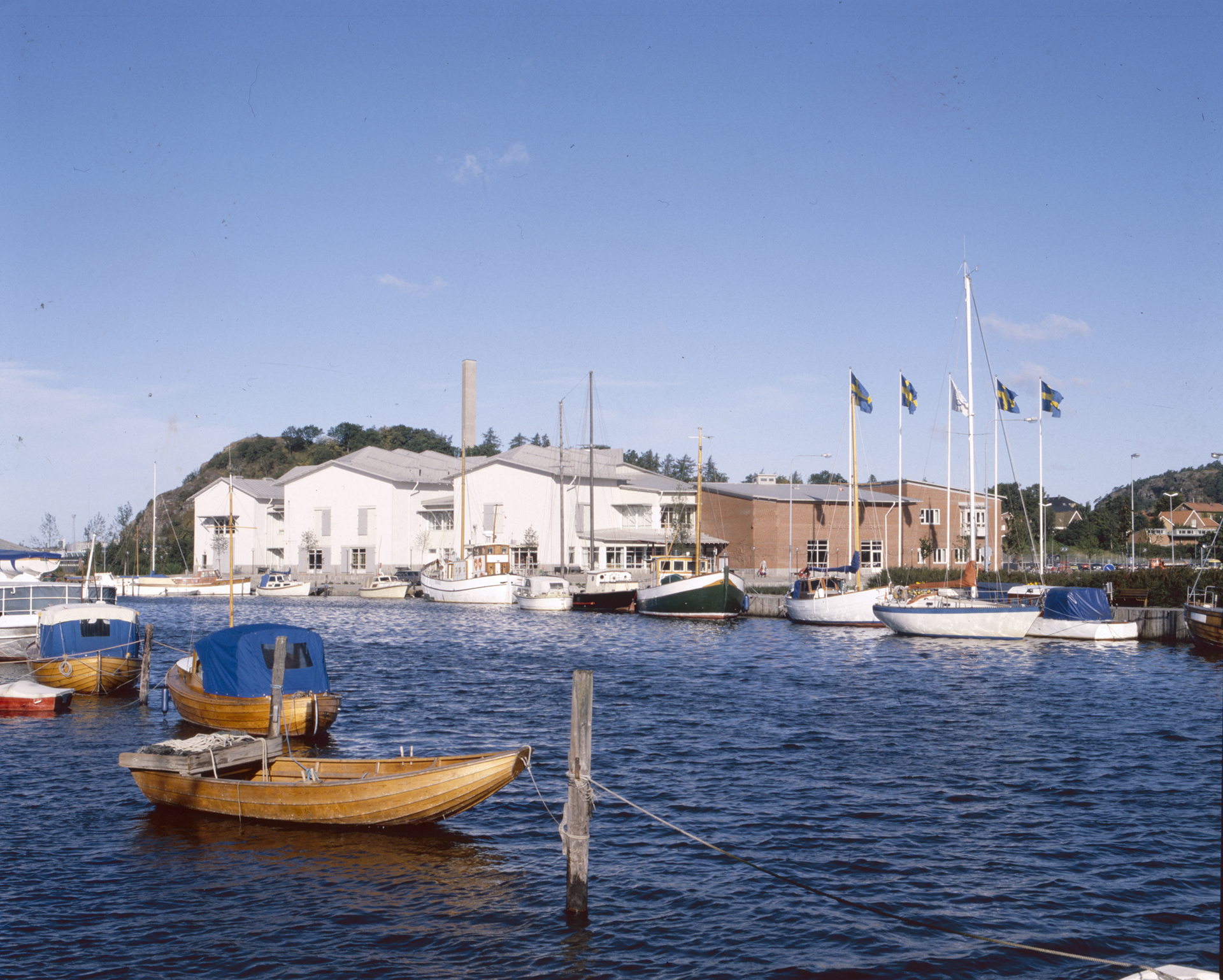 Bild av Bohusläns museum, sett från vattnet med båtar i förgrunden.