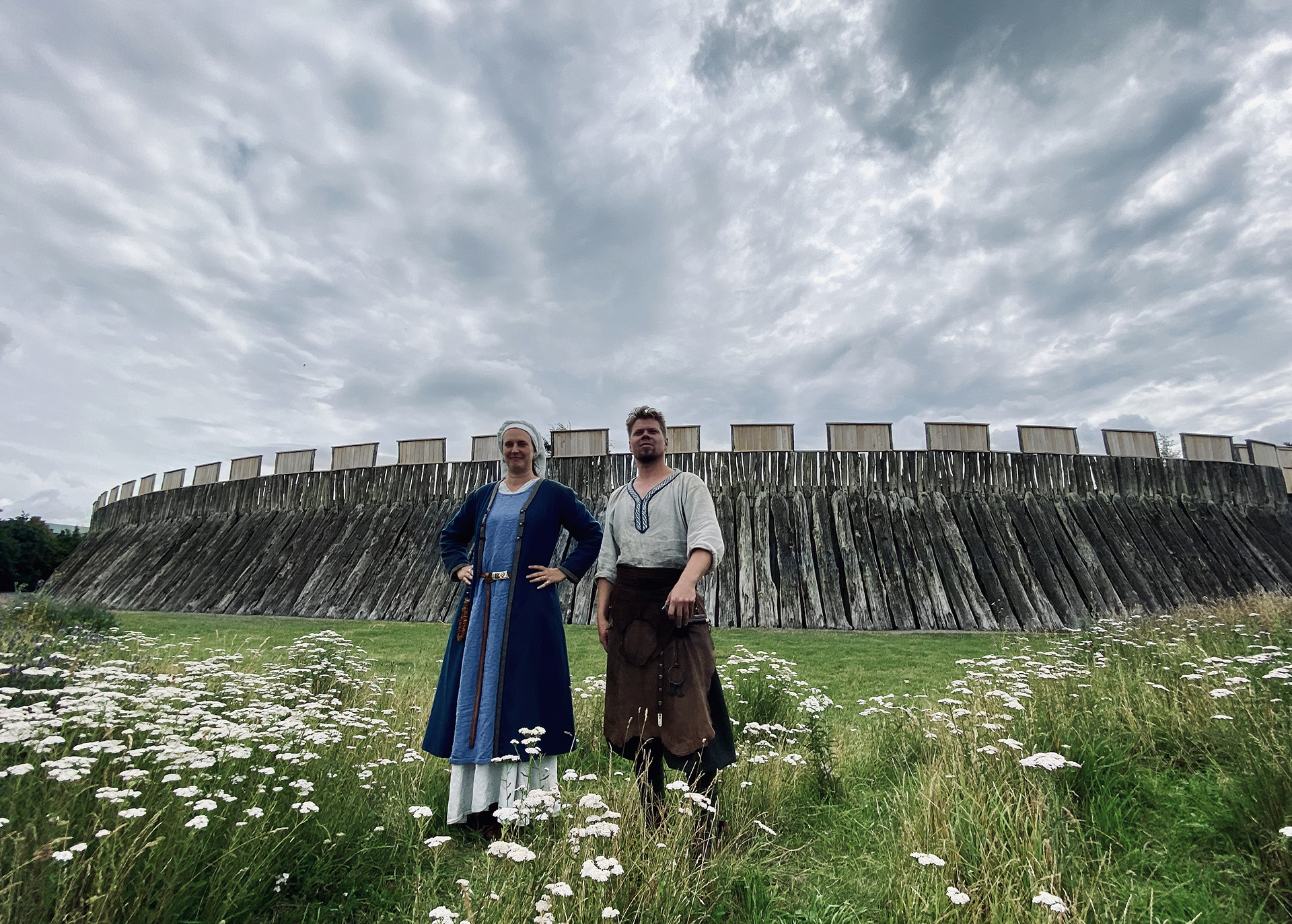 Bild av två personer i vikingatida kläder framför Trelleborgen i Trelleborg.