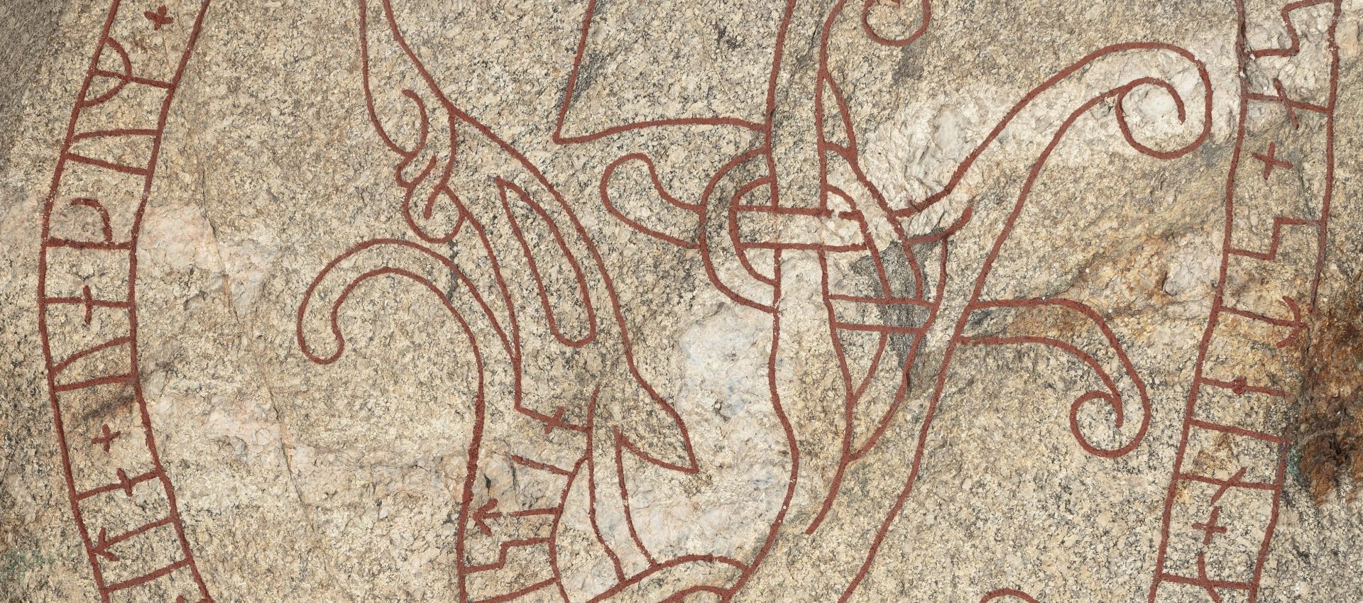 Detaljbild av en runsten av granit mer rödfärgade runslingor.
