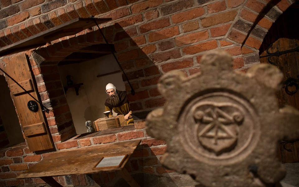 En docka föreställande en man som står i en medeltida handelsbod.