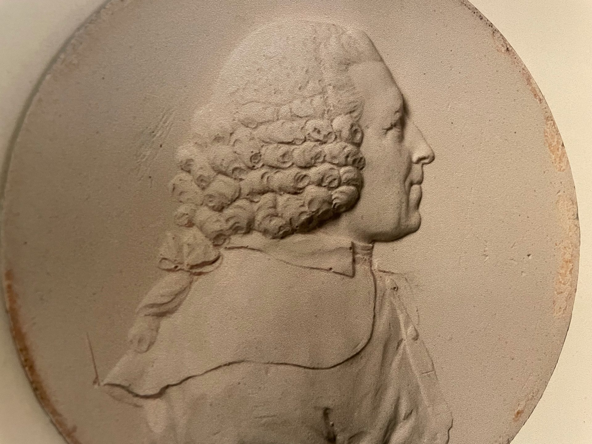 reliefporträtt av man i profil med lockig peruk