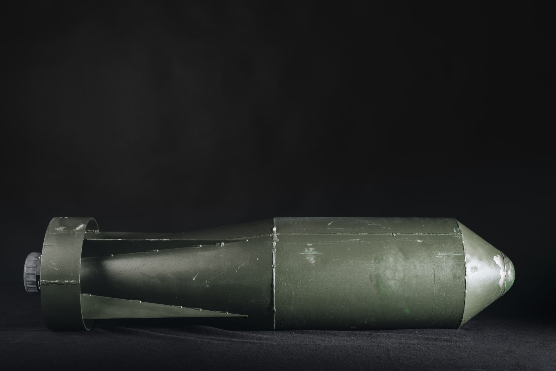 En mörkgrå cylinderformad bomb med styrfenor.