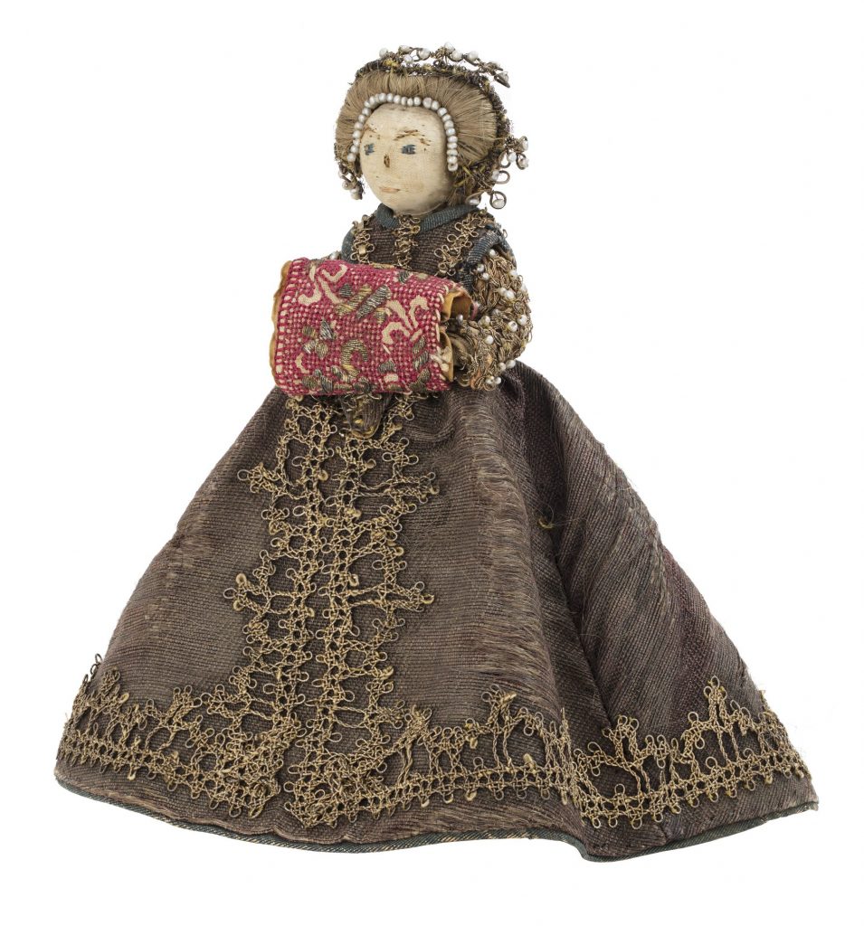 En docka av tyg med fin klänning med broderier och pärlor i håret.