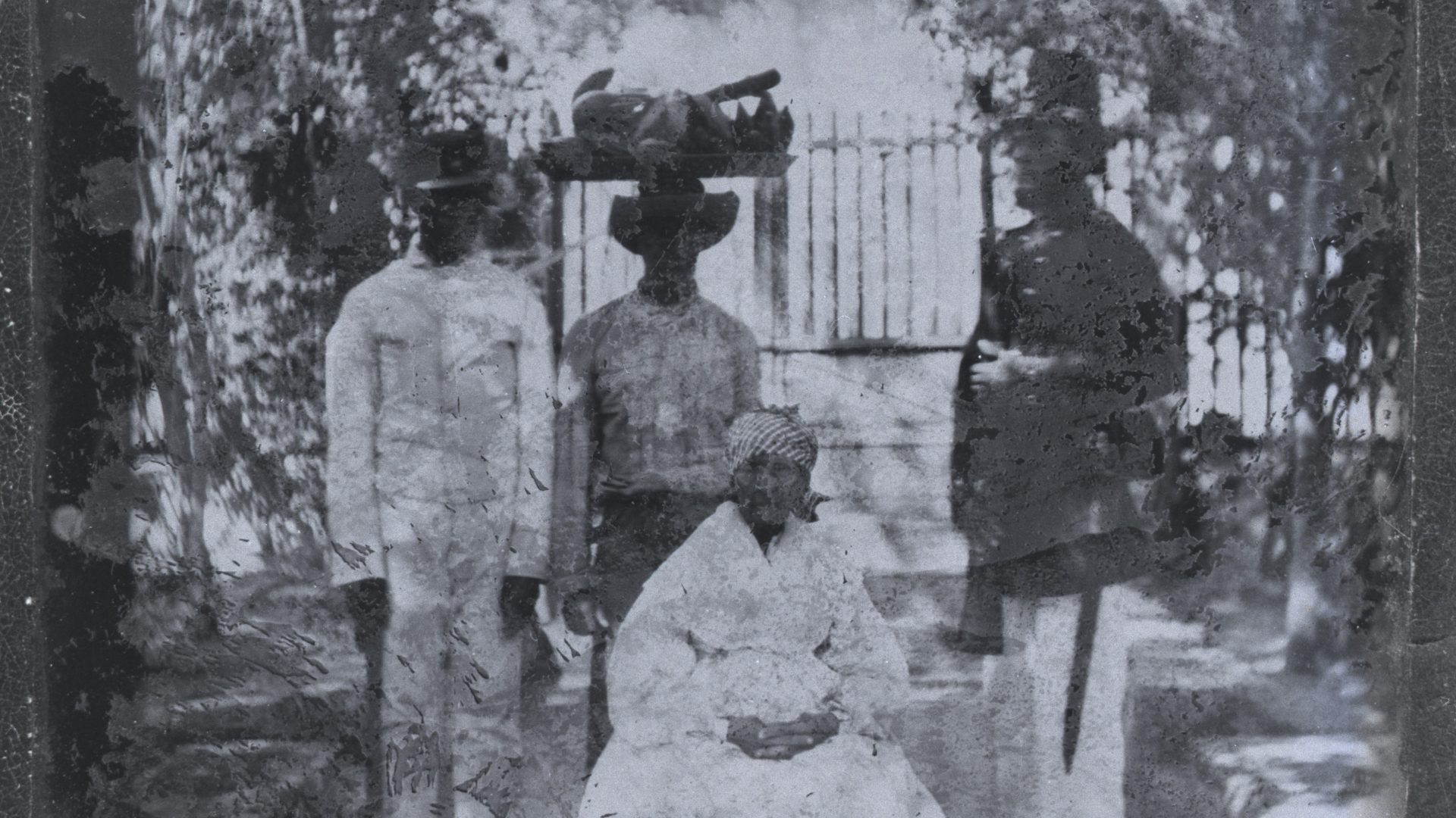 Svartvitt foto på en sittande kvinna och tre stående män.