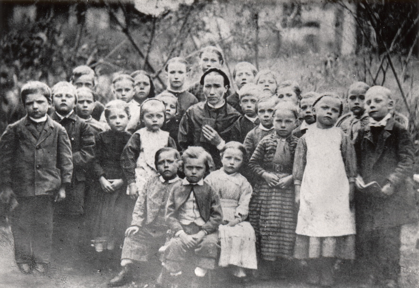 En skolklass med barn i sjuårsåldern som står runt sin lärarinna.