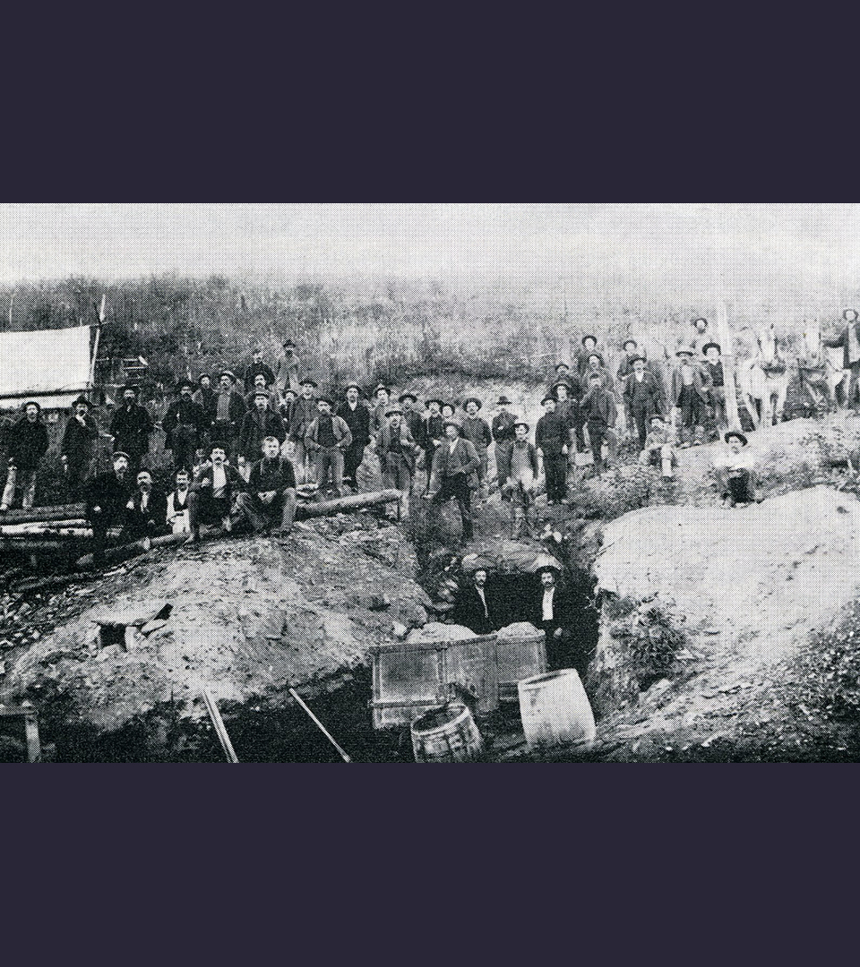 Svartvitt foto som visar en grupp män och deras guldgrävarutrustning.