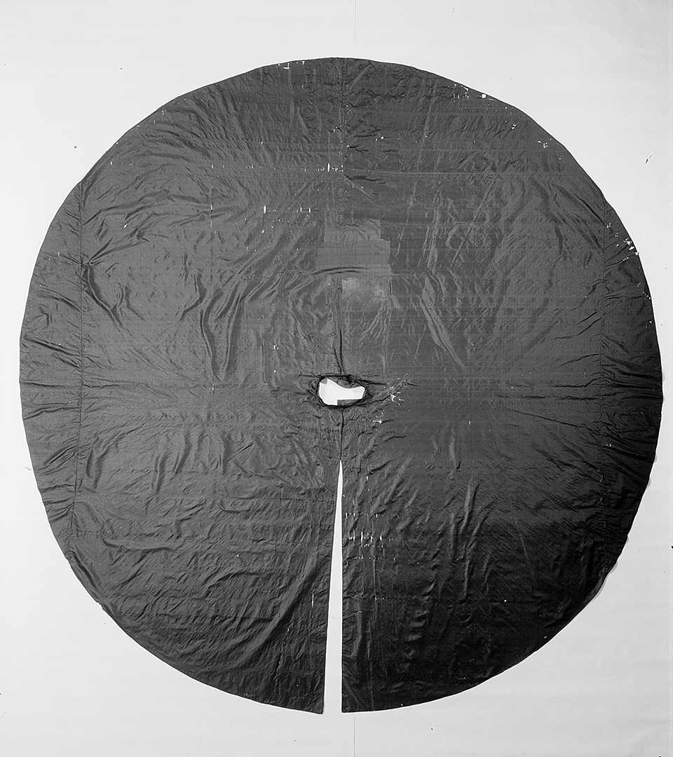 Ett cirkelrunt svar tyg, med en slits i och ett hål i mitten.