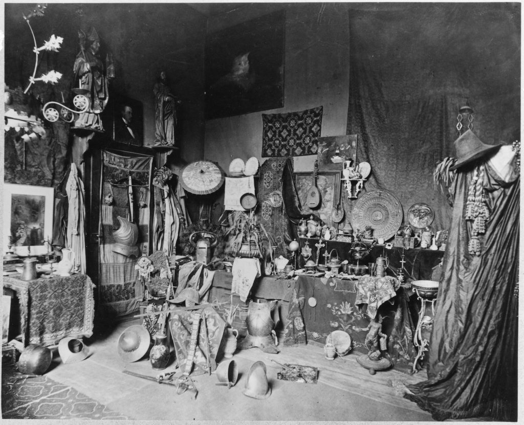 Ett svartvitt fotografi av ett rum fyllt med föremål.