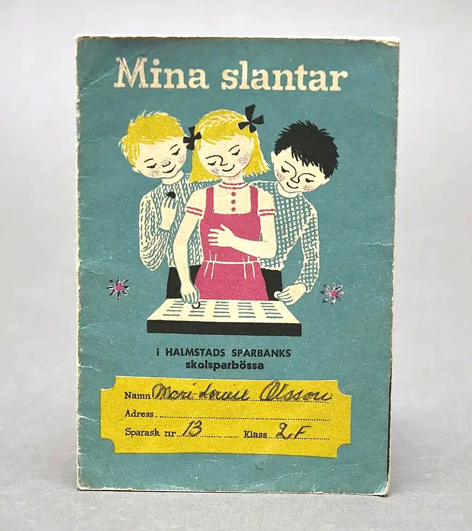 En liten bok med texten "Mina slantar" och en teckning på tre barn som stoppar pengar i en skolsparbössa.