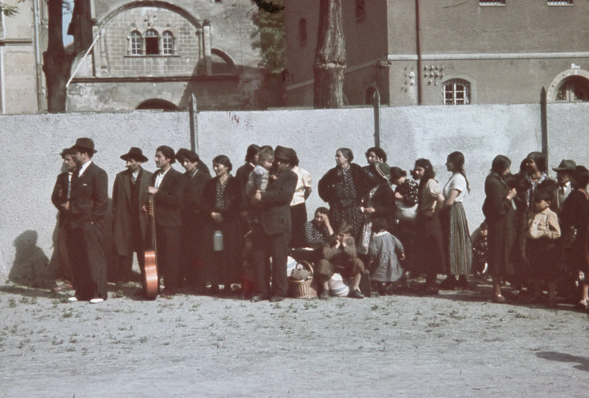 Män, kvinnor och barn stående i en kö längs med en mur.